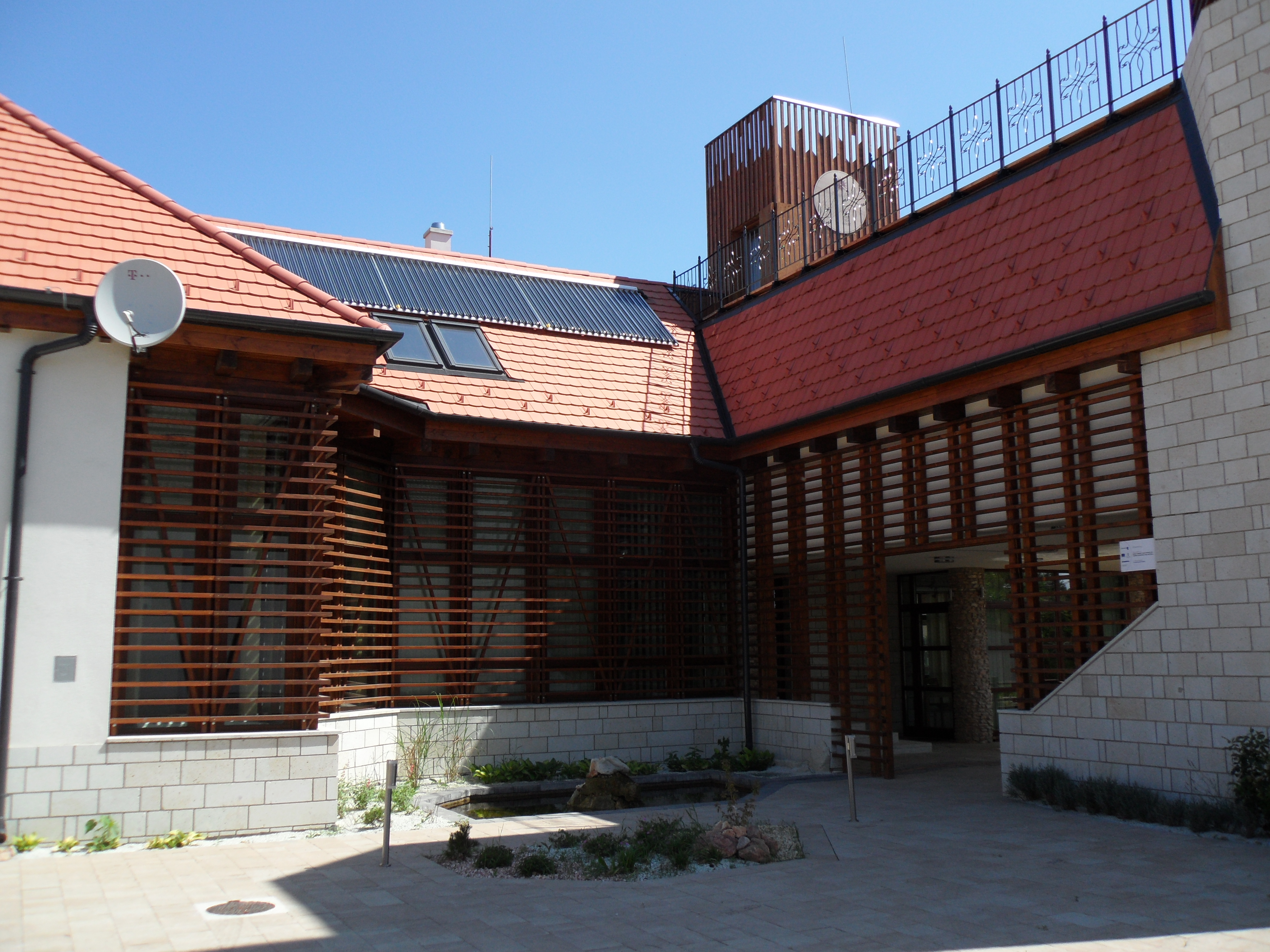 Hybrid rendszer: vizes napkollektorok, 3000 l puffertartály, 300 l indirekt HMV tartály, 90 kW kondenzációs gázkazán, vegyestüzelésű kazán, szintenkénti fűtés- és HMV vezérlés, rendszer átalakítás és részleges felújítás