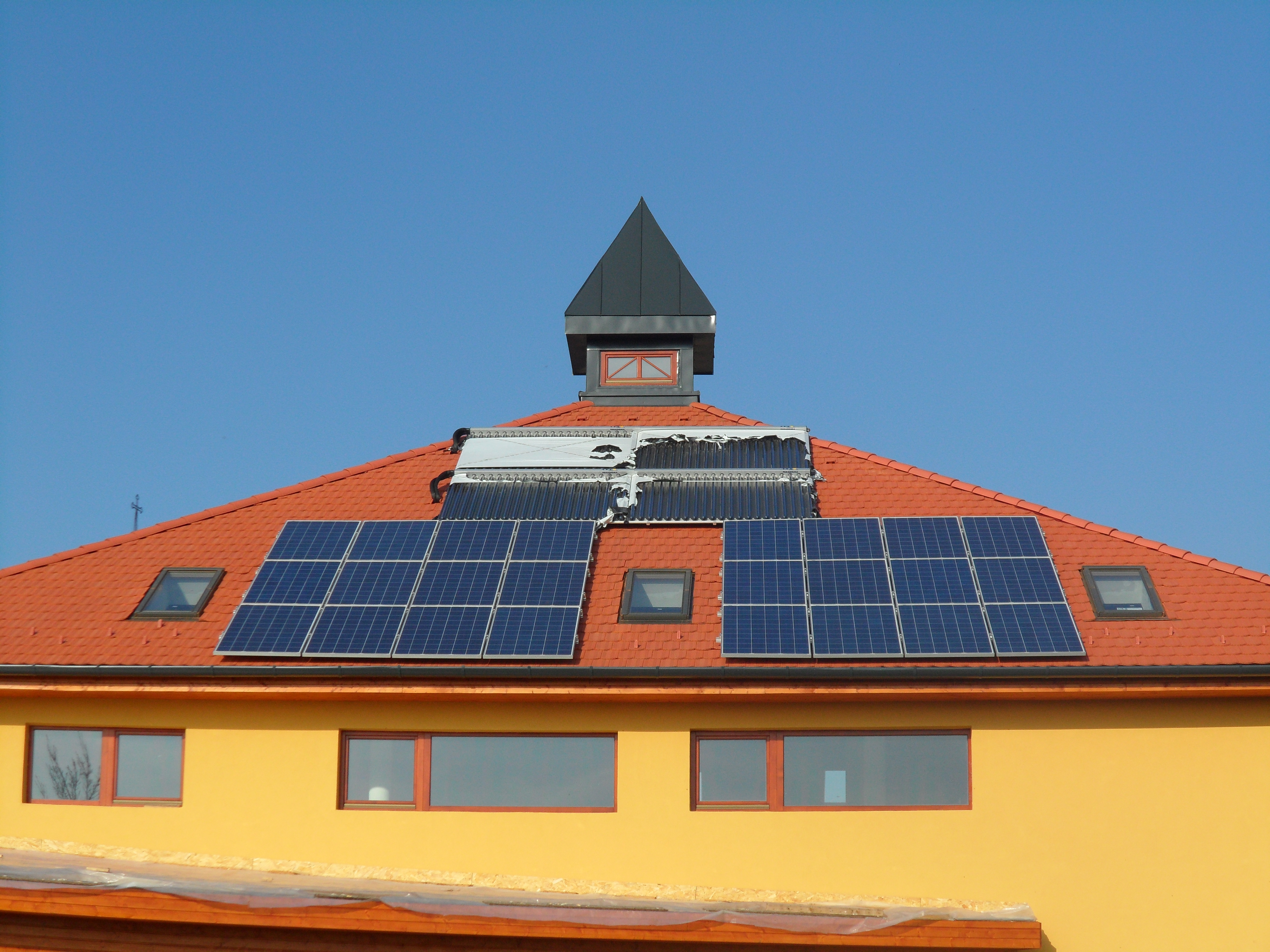 Alapítványi iskola — ipari hybrid rendszer: vizes napkollektorok, 3000 l és 2000 l rétegtöltésű puffertartályok, ipari apríték kazán, komplett vizesblokkokkal, megújuló energiákat bemutató épület gépészet, radiátoros és padlófűtés